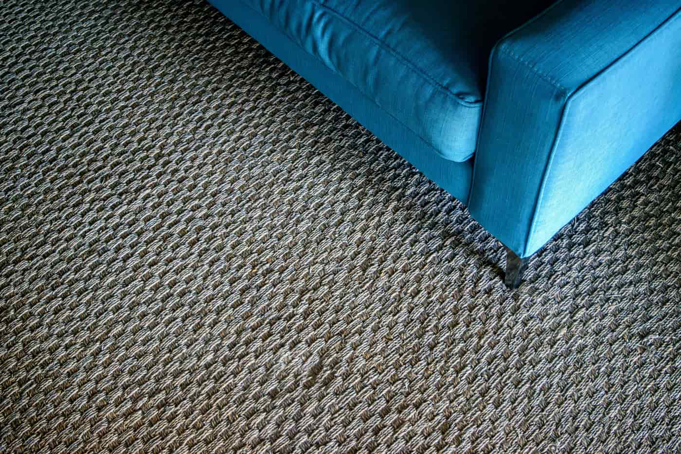A corner of a living room with a textured woven carpet