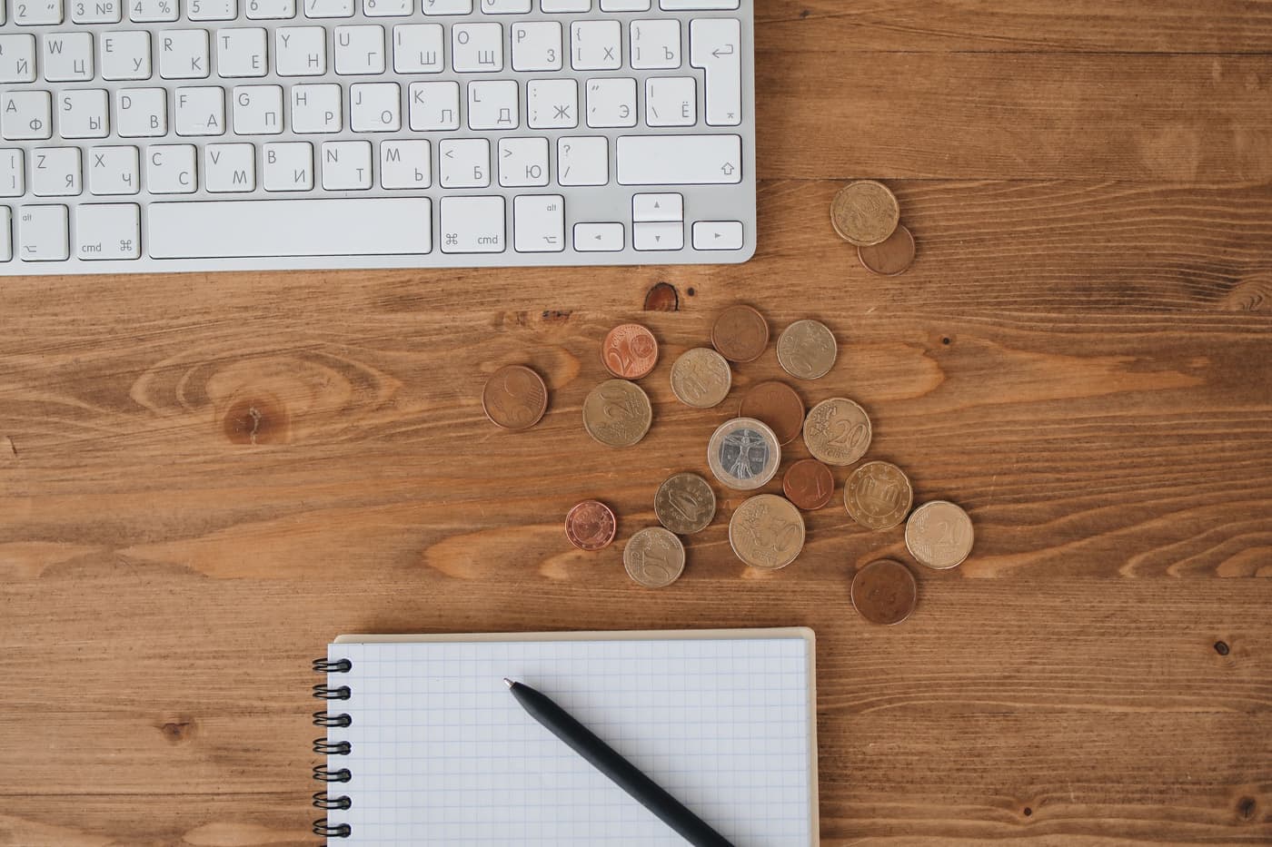 Coins and a notebook on a wooden desk seen from above
