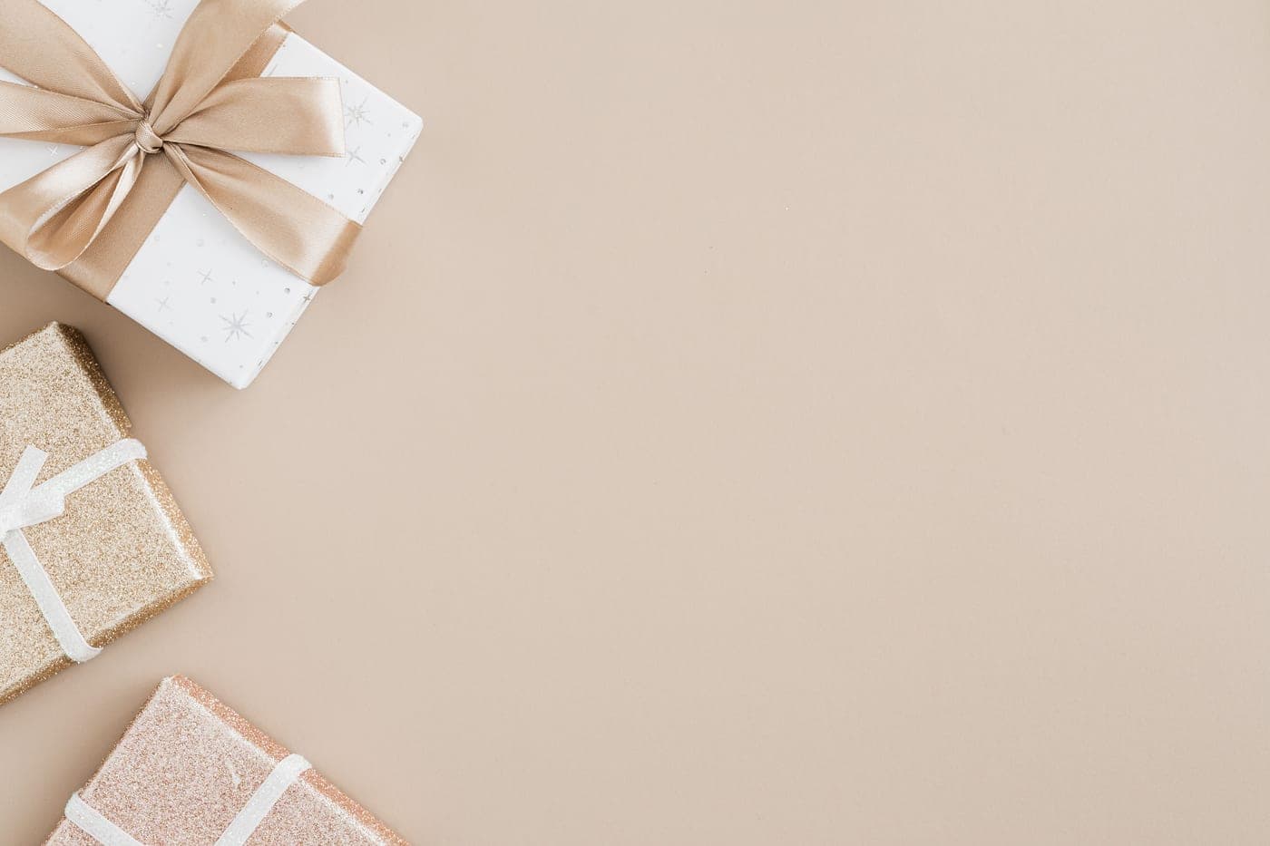 Gift boxes with ribbons arranged on a beige background