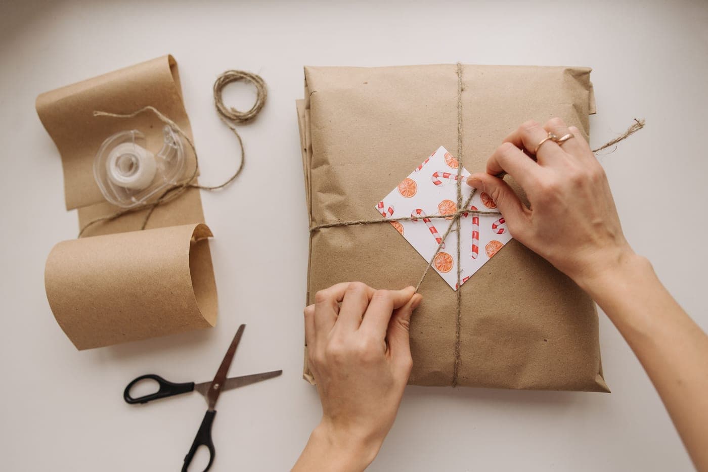 Hands tying string around a parcel wrapped in brown paper