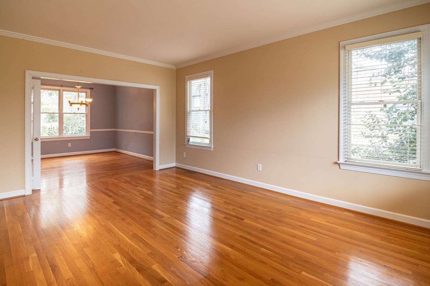 An empty room with wooden floors and large windows