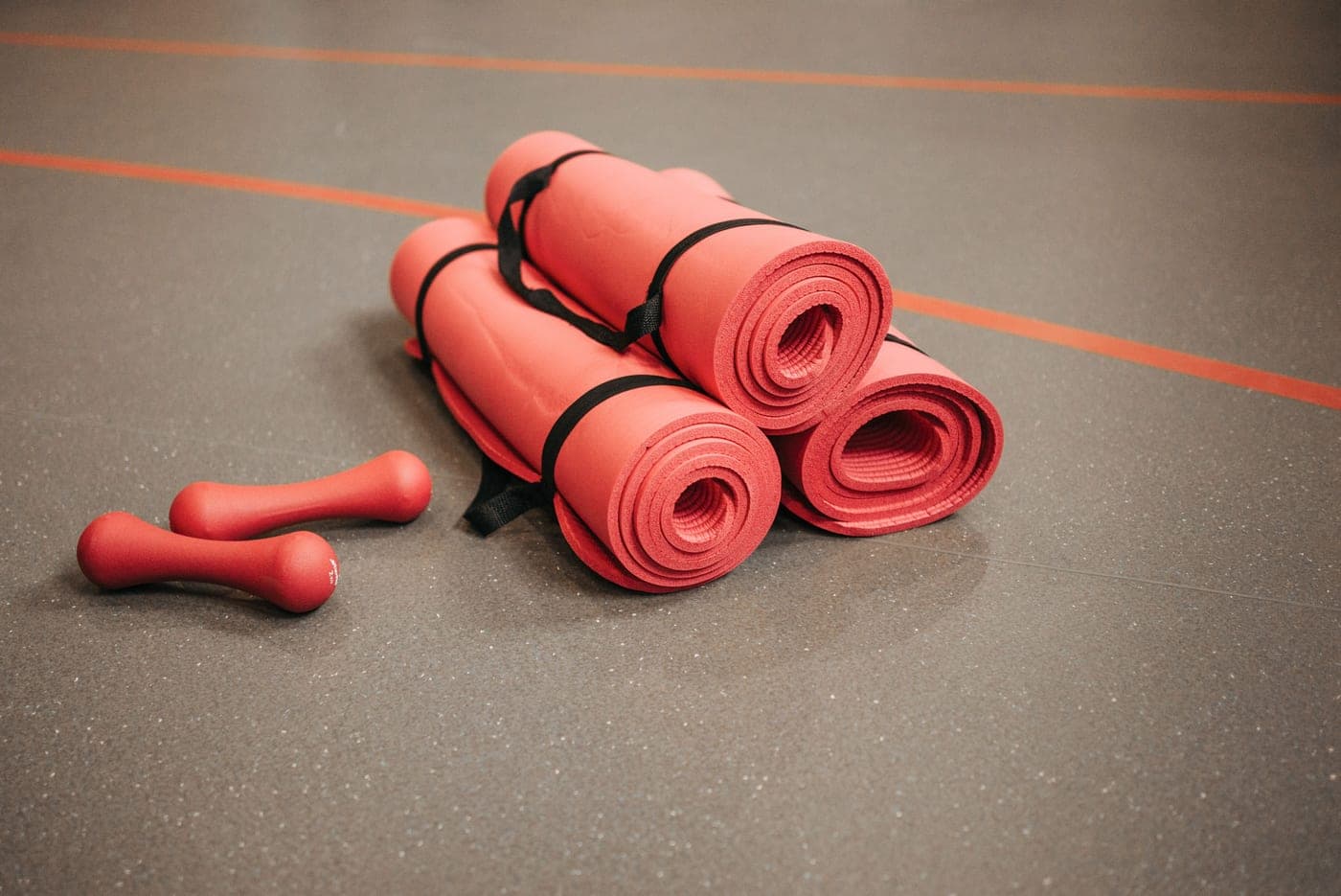 Exercise mats and dumbbells laid out on a gym floor