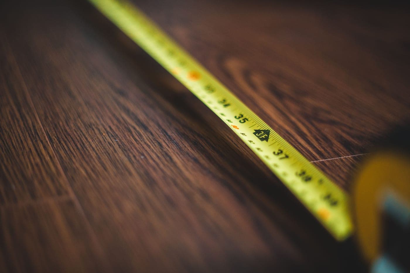 A tape measure extended across a dark wooden floor