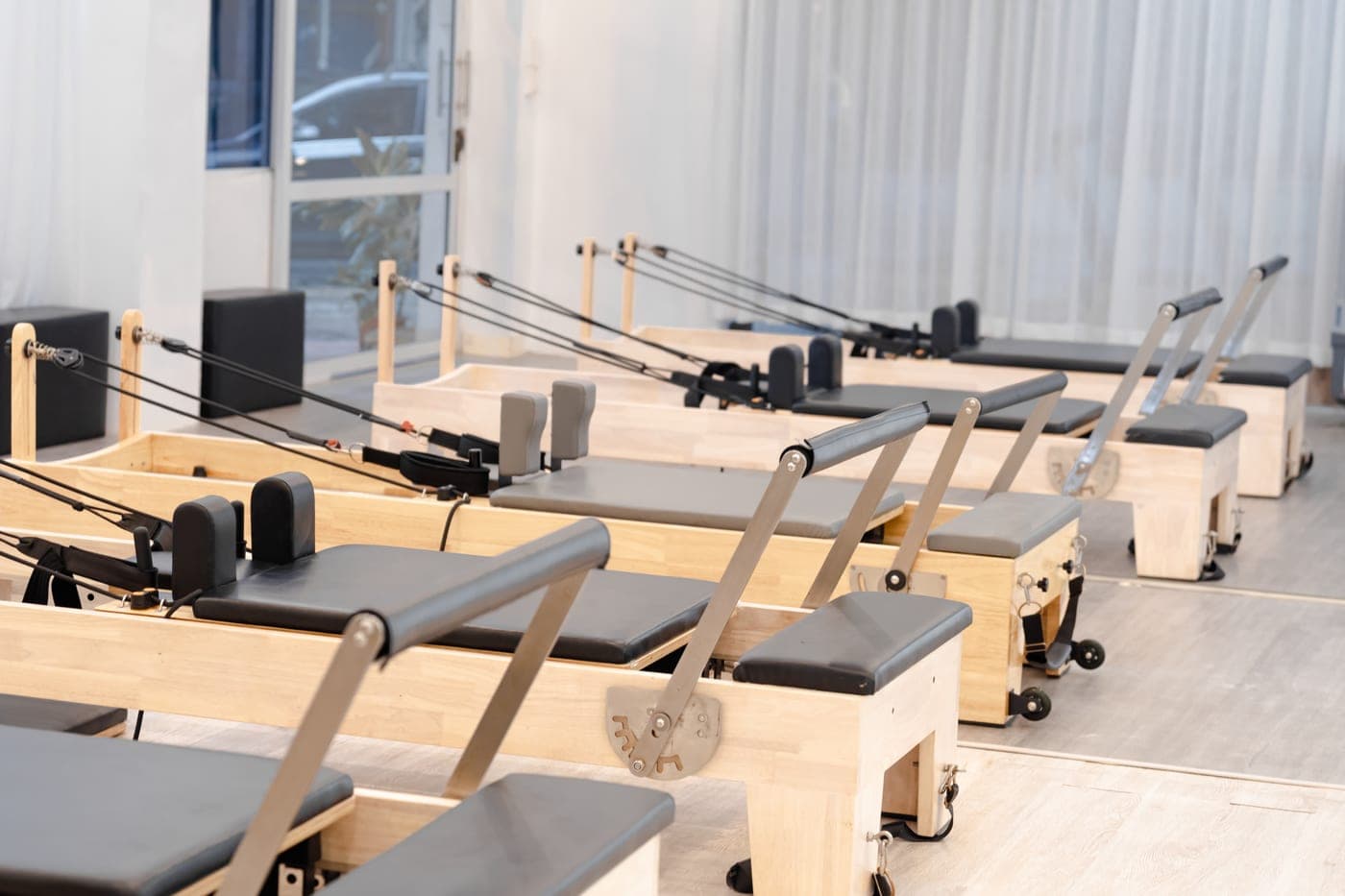 A contemporary pilates studio with several wooden reformers