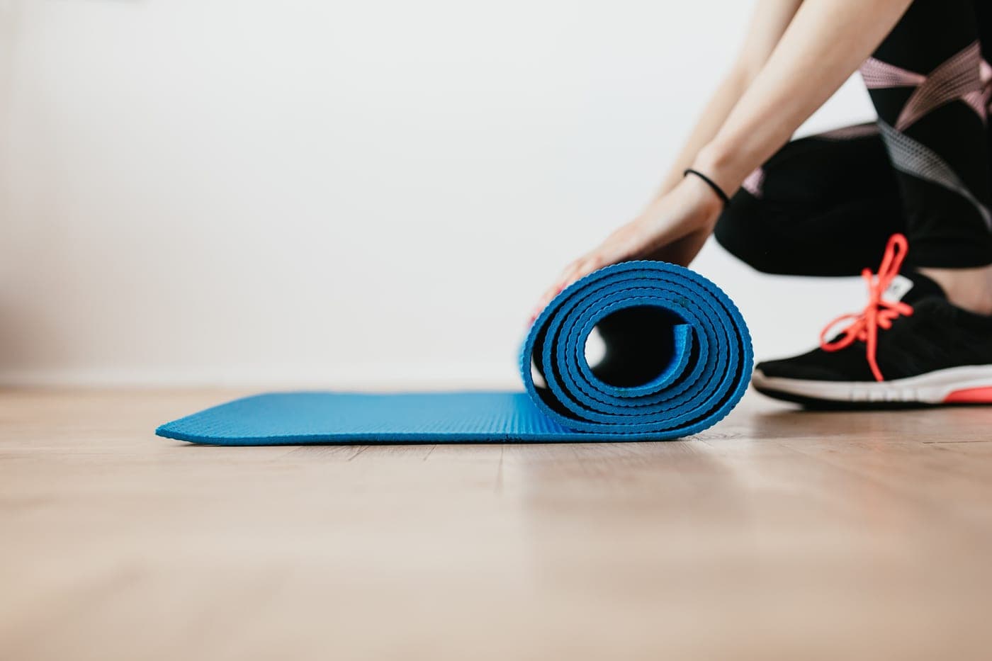 Someone unfolding an exercise mat on an indoor floor