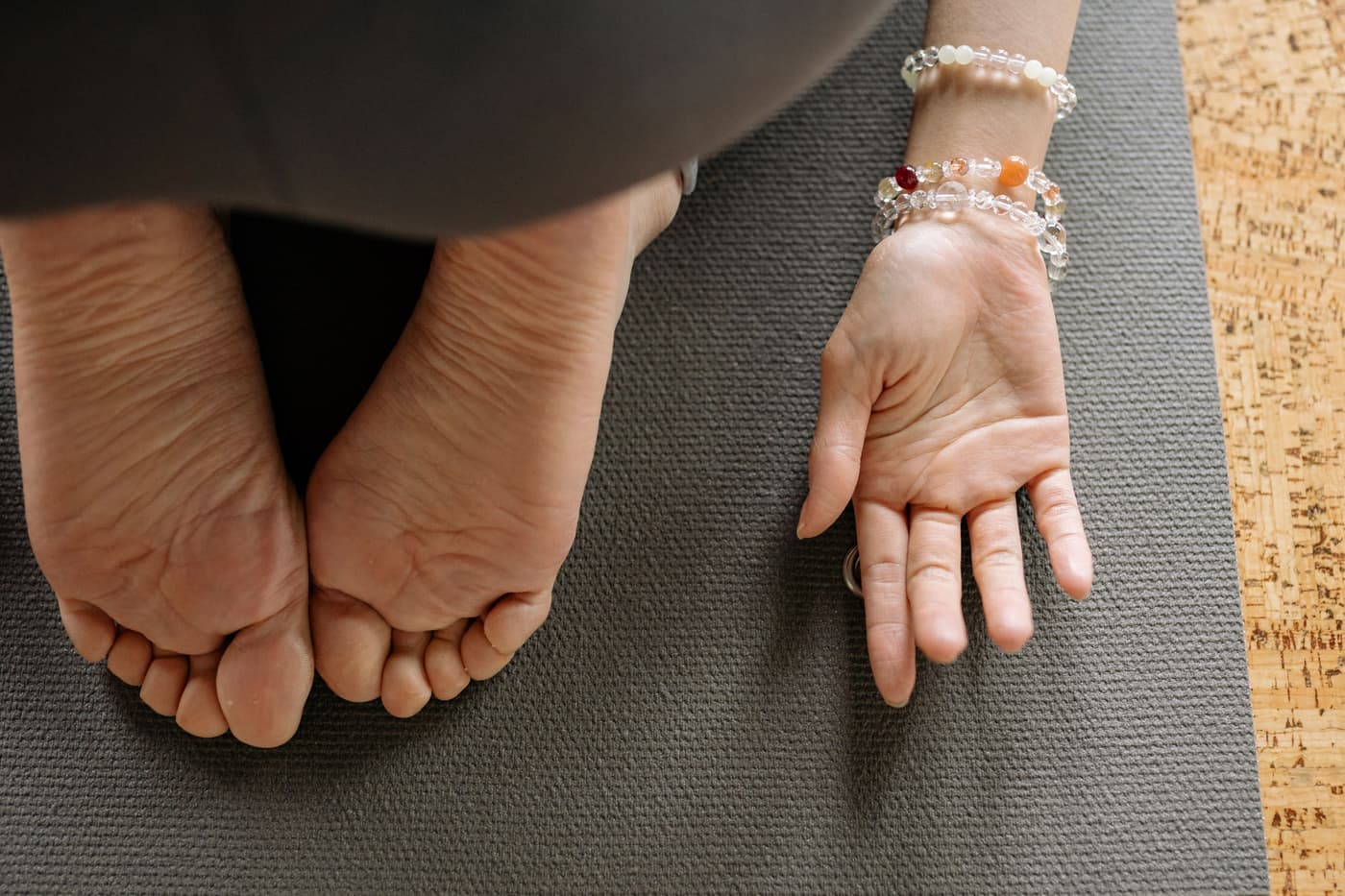 Close-up of a hand and feet on a mat during a floor practice