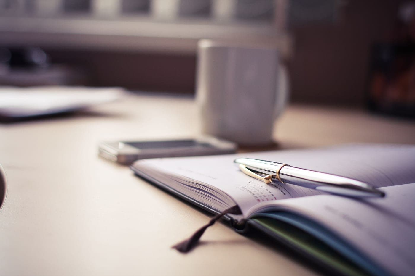 An open planner and pen on a desk in morning light