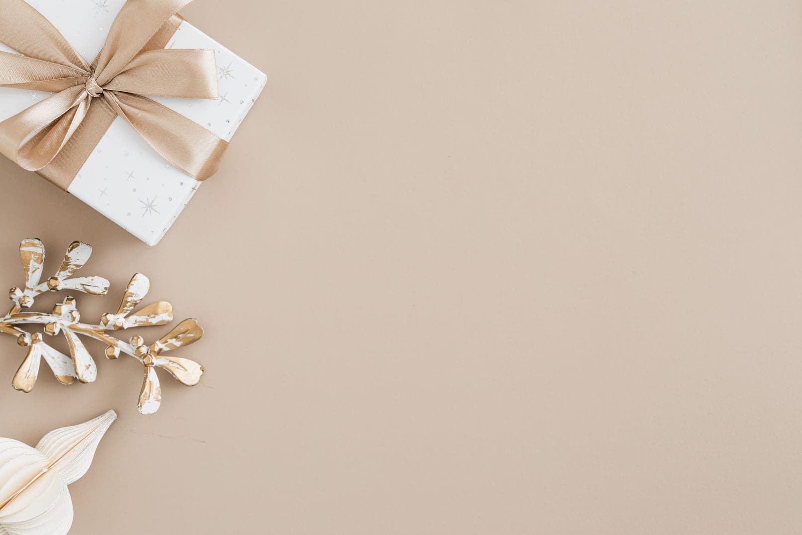 A wrapped gift box with a bow on a plain beige background