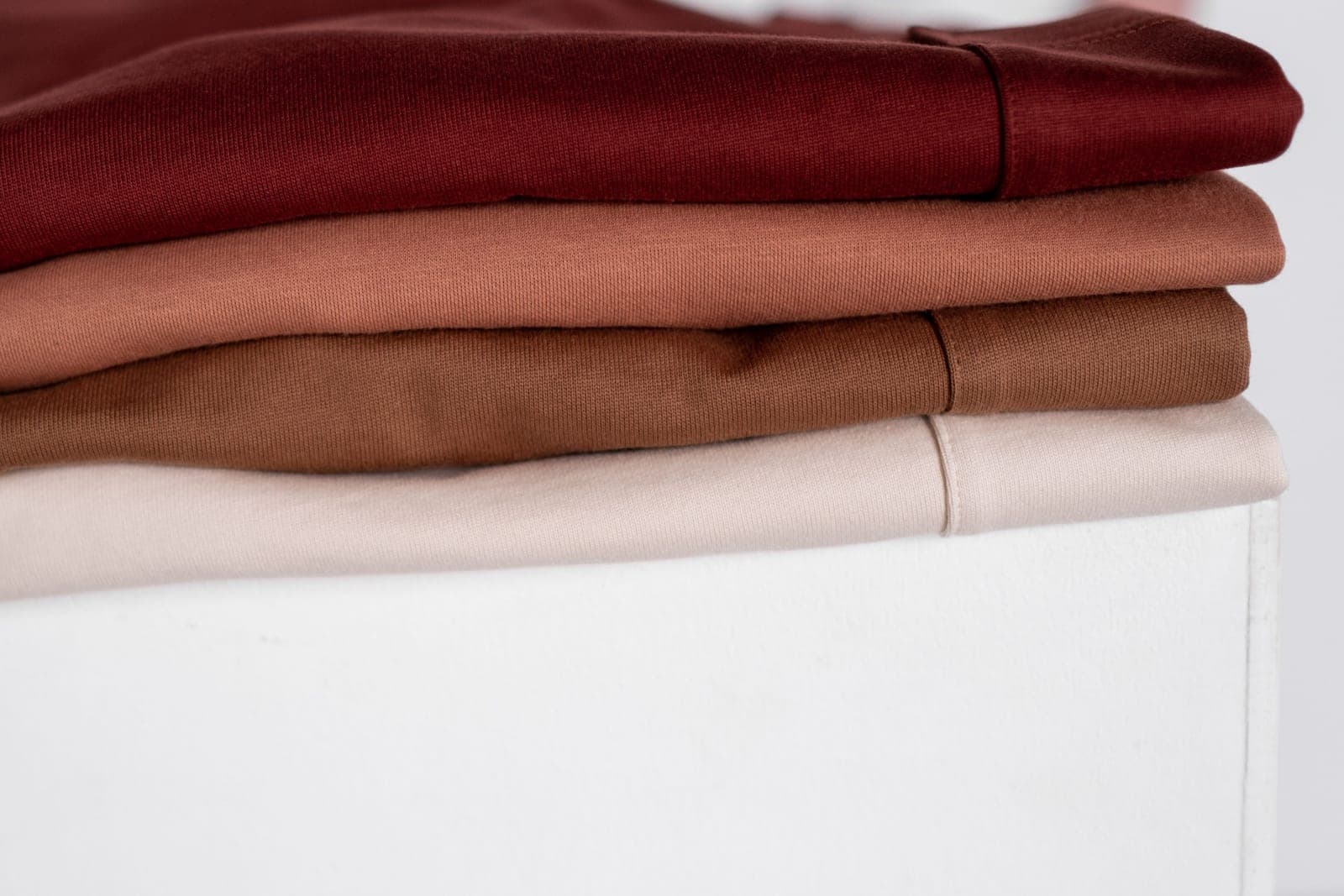 Close-up of neatly stacked neutral-tone clothing, showing the fabric textures