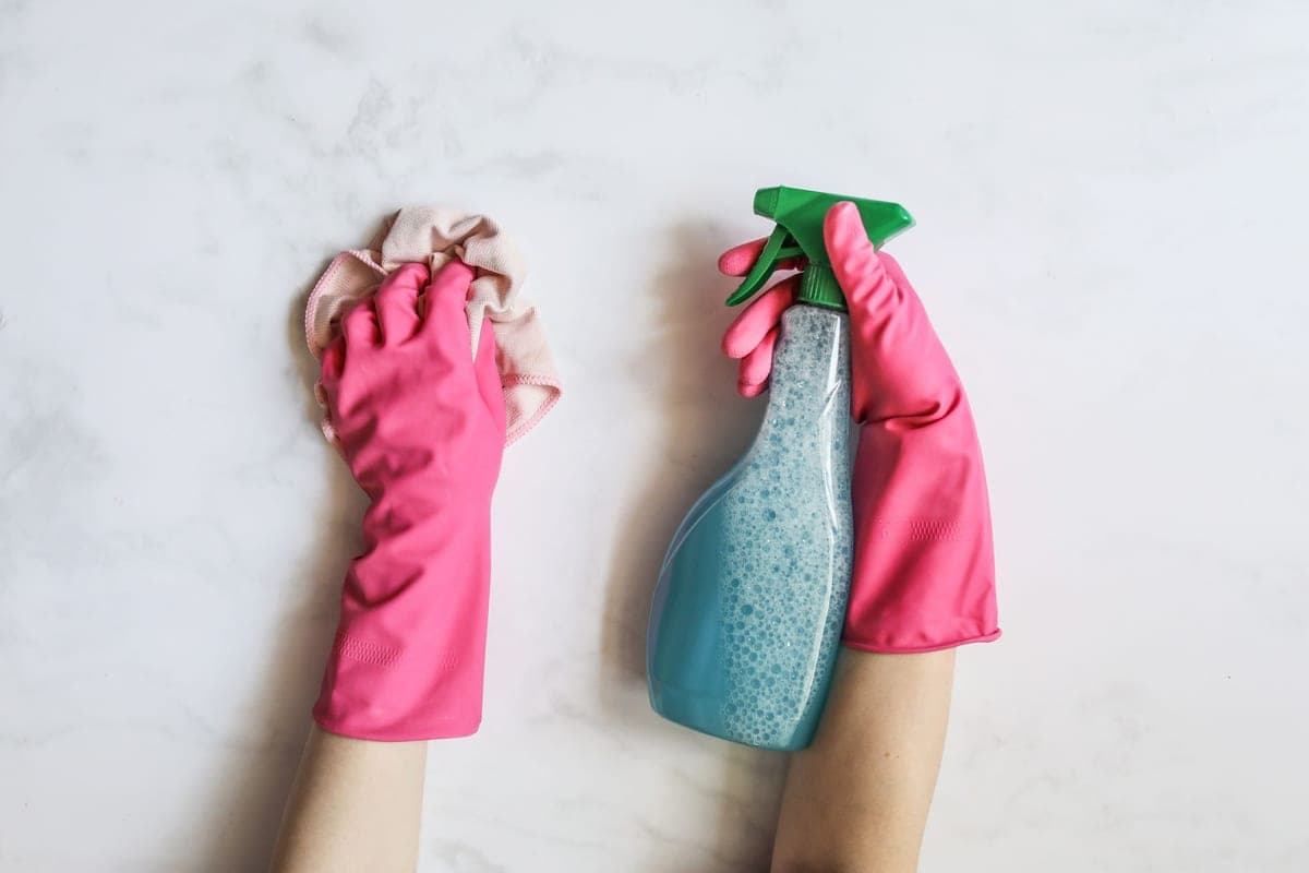 Stock photo: a gloved hand holding a spray bottle against a white background
