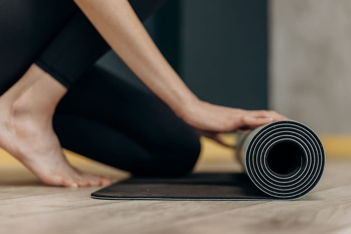 Stock photo: a rolled exercise mat being lifted from a wooden floor