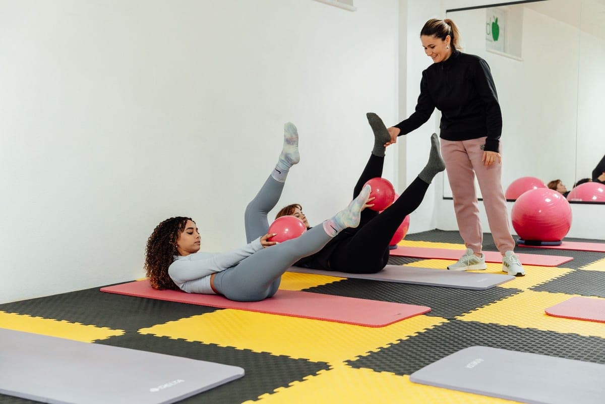 Stock photo: a mat class holding small pink balls between the hands and knees