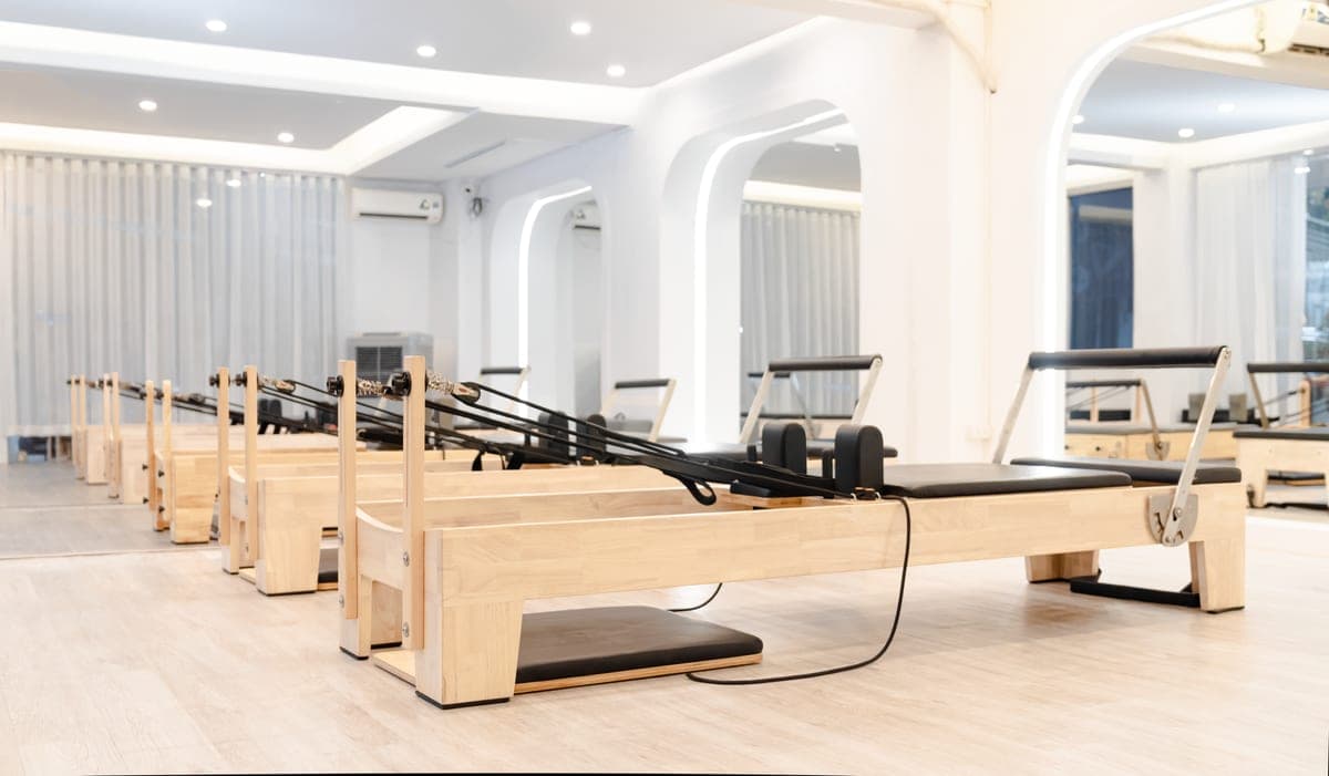 Stock photo: wooden pilates reformers lined up in a bright studio