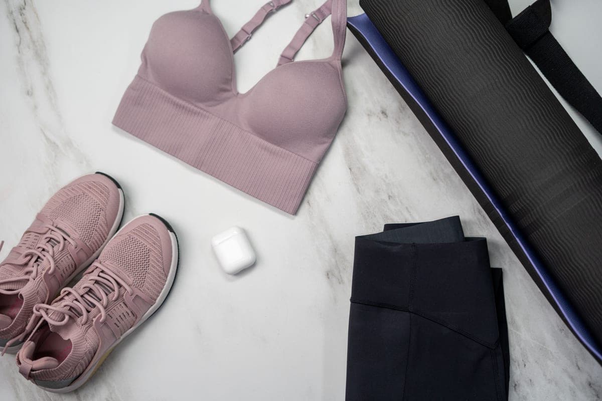 Stock photo: a sports bra, sneakers, mat and earphones laid out on a pale surface