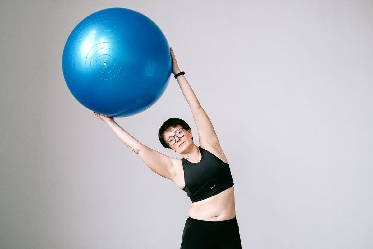 Stock photo: someone holding a large blue stability ball overhead against a plain wall